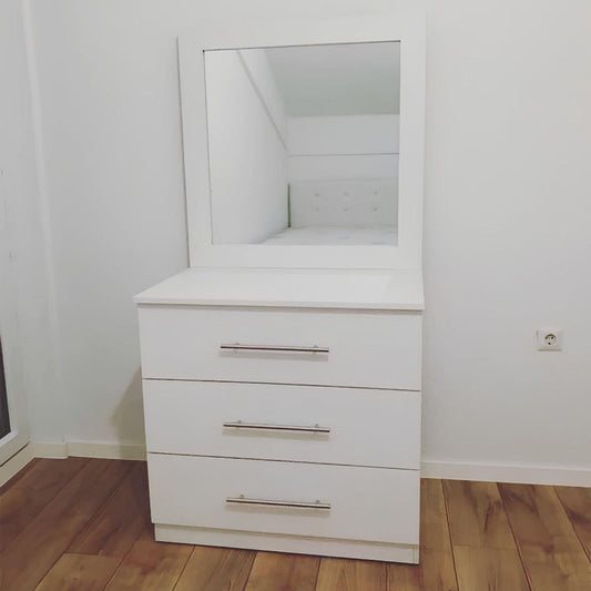 White dresser with mirror on a wooden floor against a white wall