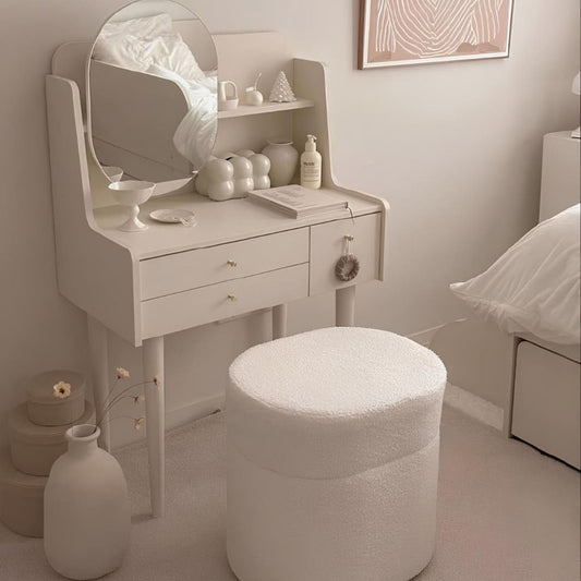 White vanity table with mirror and stool in a bedroom setting