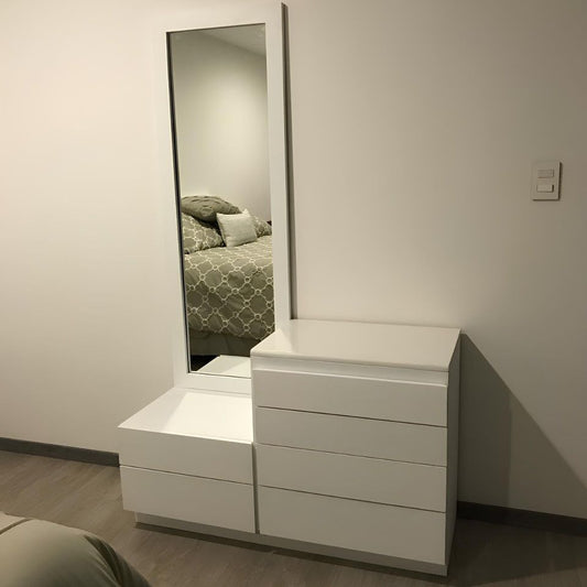 White dresser with a full-length mirror reflecting a bed in a bedroom setting.