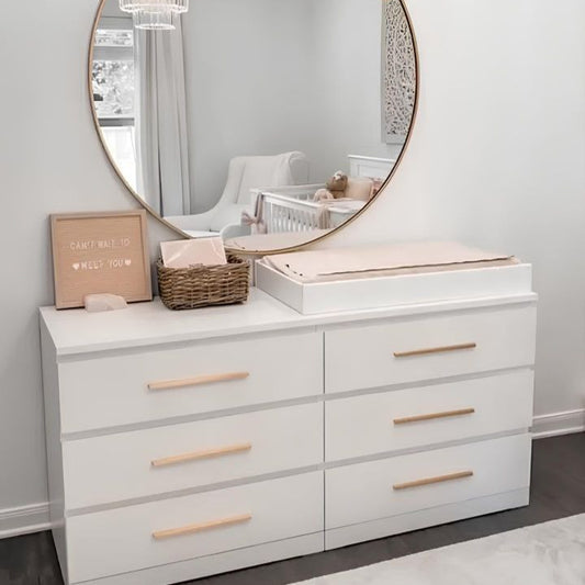 White dresser with round mirror and decorative items in a room with 'yay' wall art.